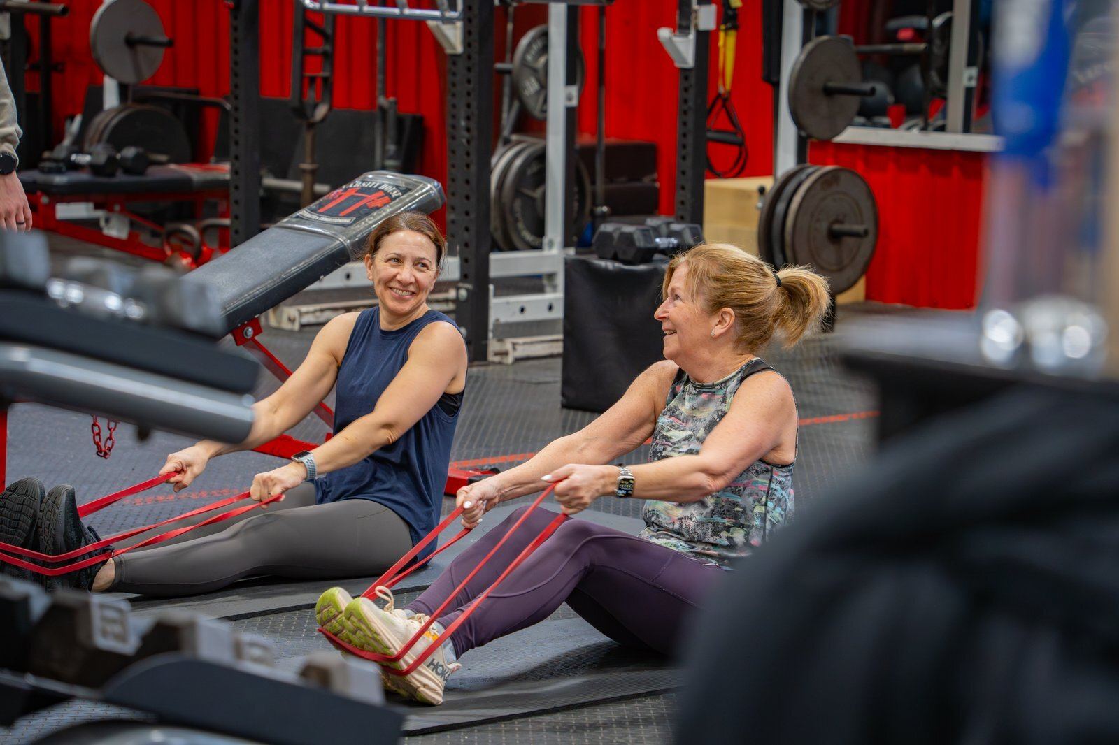 Adult members talking with a coach between sets at Varsity House Gym
