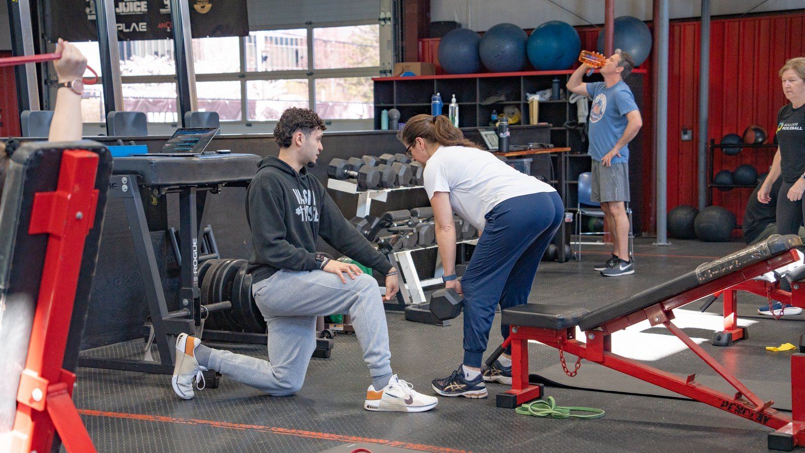 Adult woman performing a kettlebell goblet squat with coach guidance
