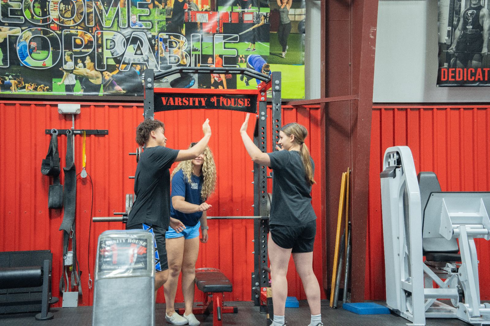 Two youth athletes high-fiving with a Varsity House coach after a successful set