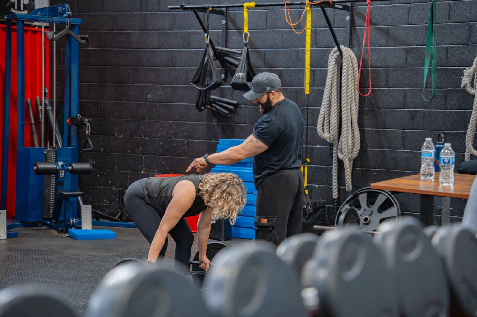 Coach cueing an adult member on deadlift setup during expert coaching
