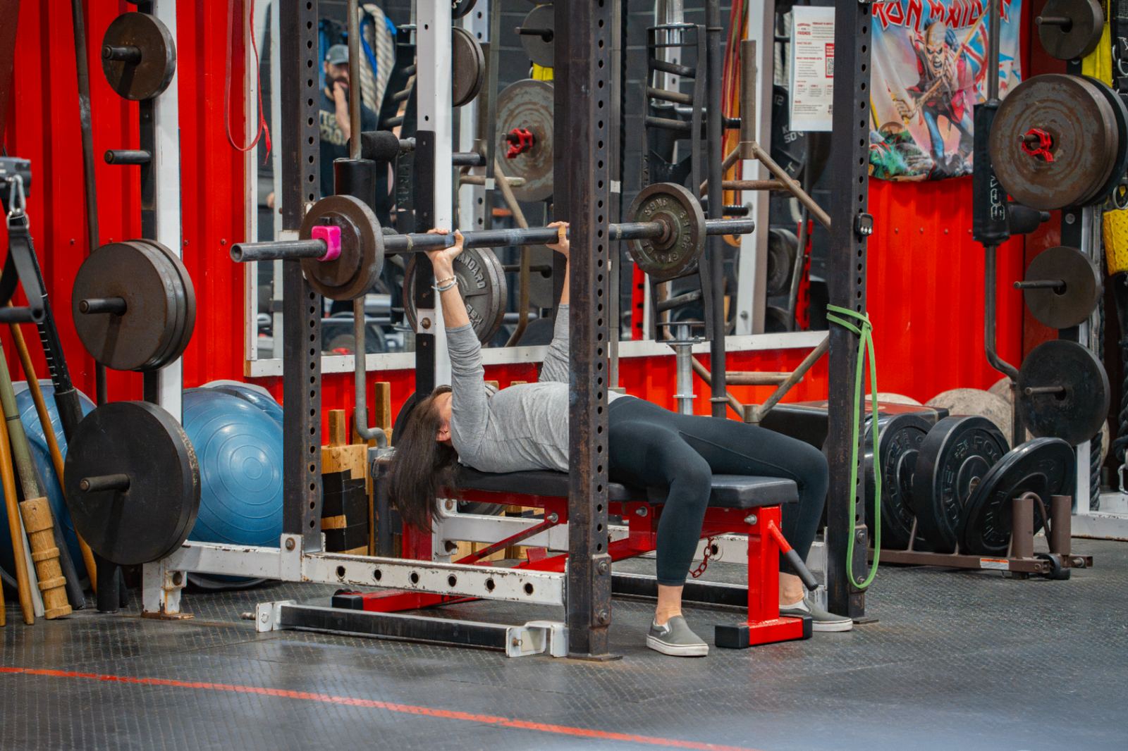 Adult member bench pressing during a scheduled small-group session at Varsity House